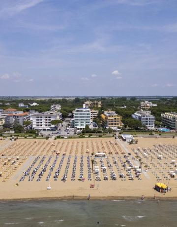 Spiaggia con ombrelloni e edifici sullo sfondo, giornata soleggiata.