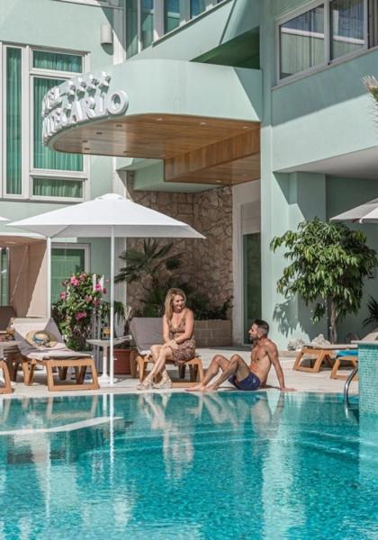 Hotel pool with people relaxing under umbrellas.