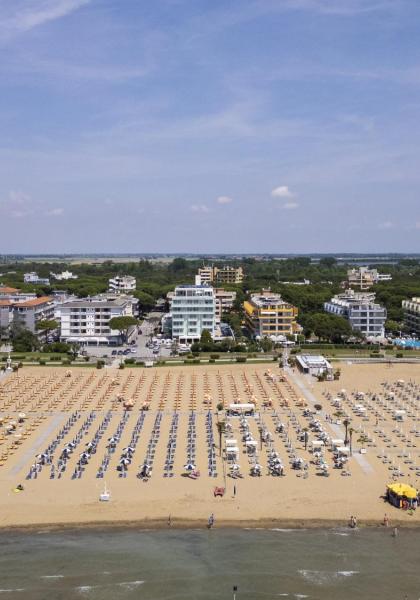 Beach with umbrellas and buildings in the background, sunny day.