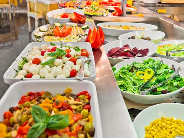 Buffet of fresh salads, vegetables, and cheeses in a restaurant.