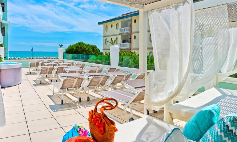 Sunny terrace with loungers, sea view, and pool.