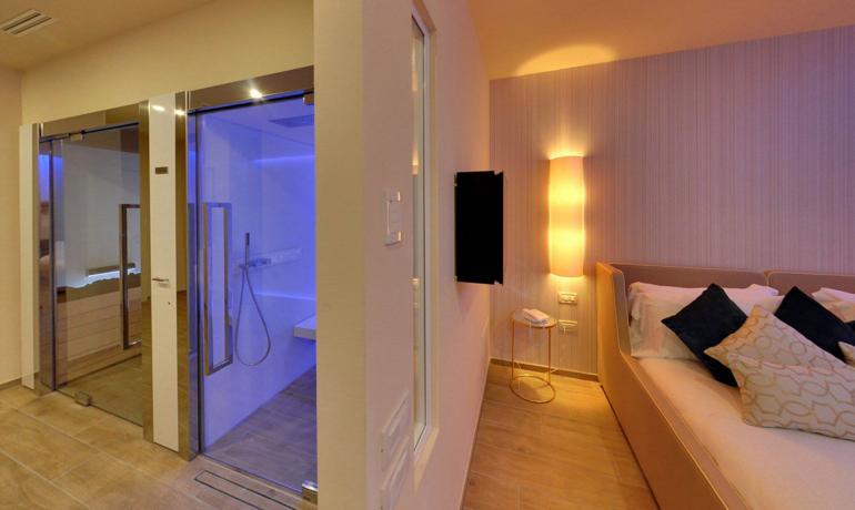 Modern room with illuminated shower and cozy bed.