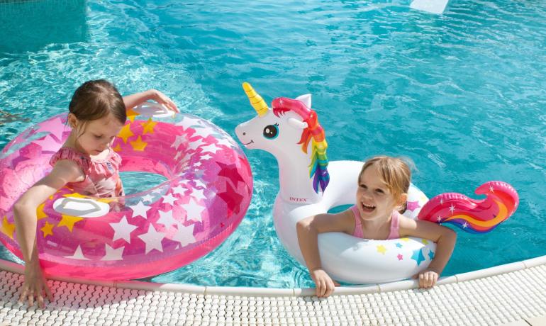 Girls in a pool with colorful inflatable rings.