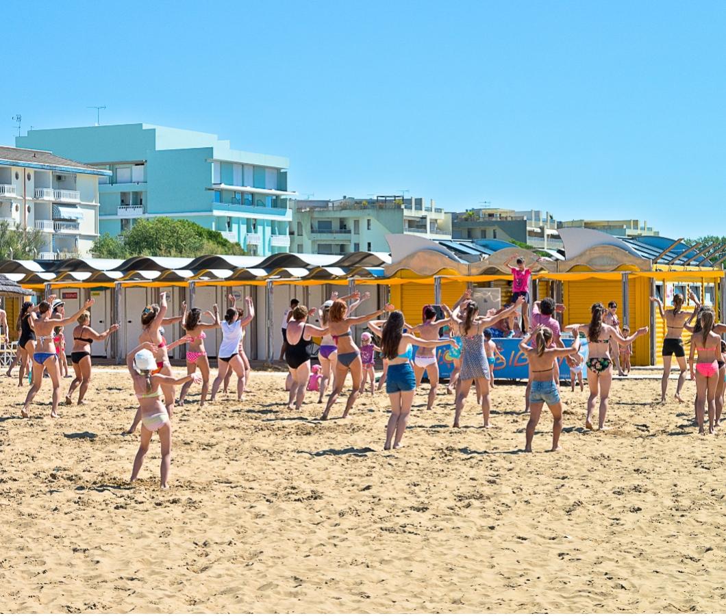 People doing group exercises on the beach under the sun.