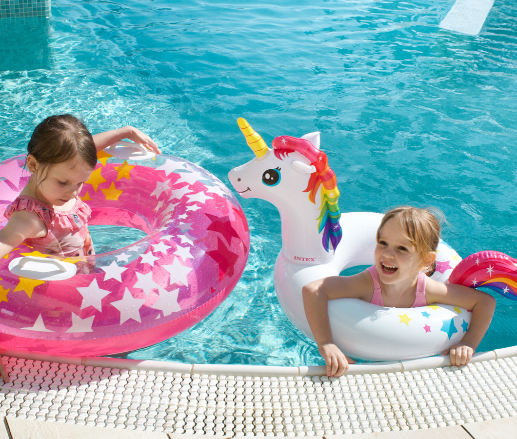 Due bambine giocano in piscina con ciambelle gonfiabili colorate.