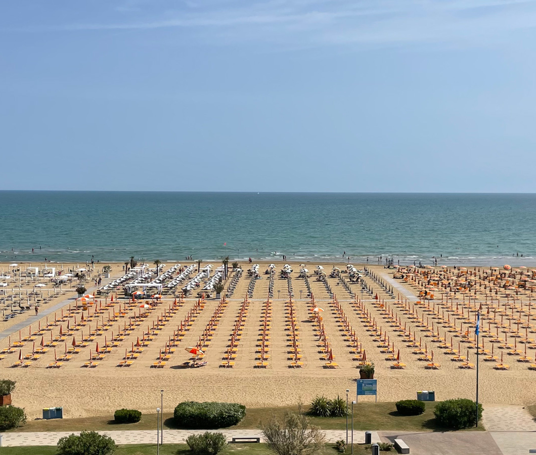 Spiaggia con ombrelloni colorati, mare calmo e cielo sereno.