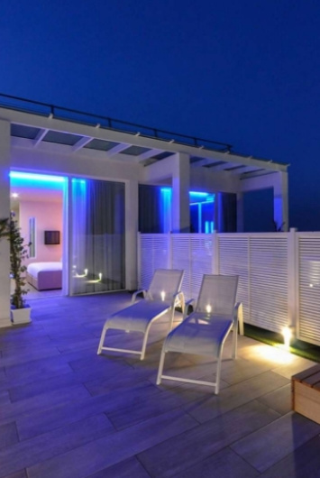 Modern terrace with blue lights and lounge chairs at night.